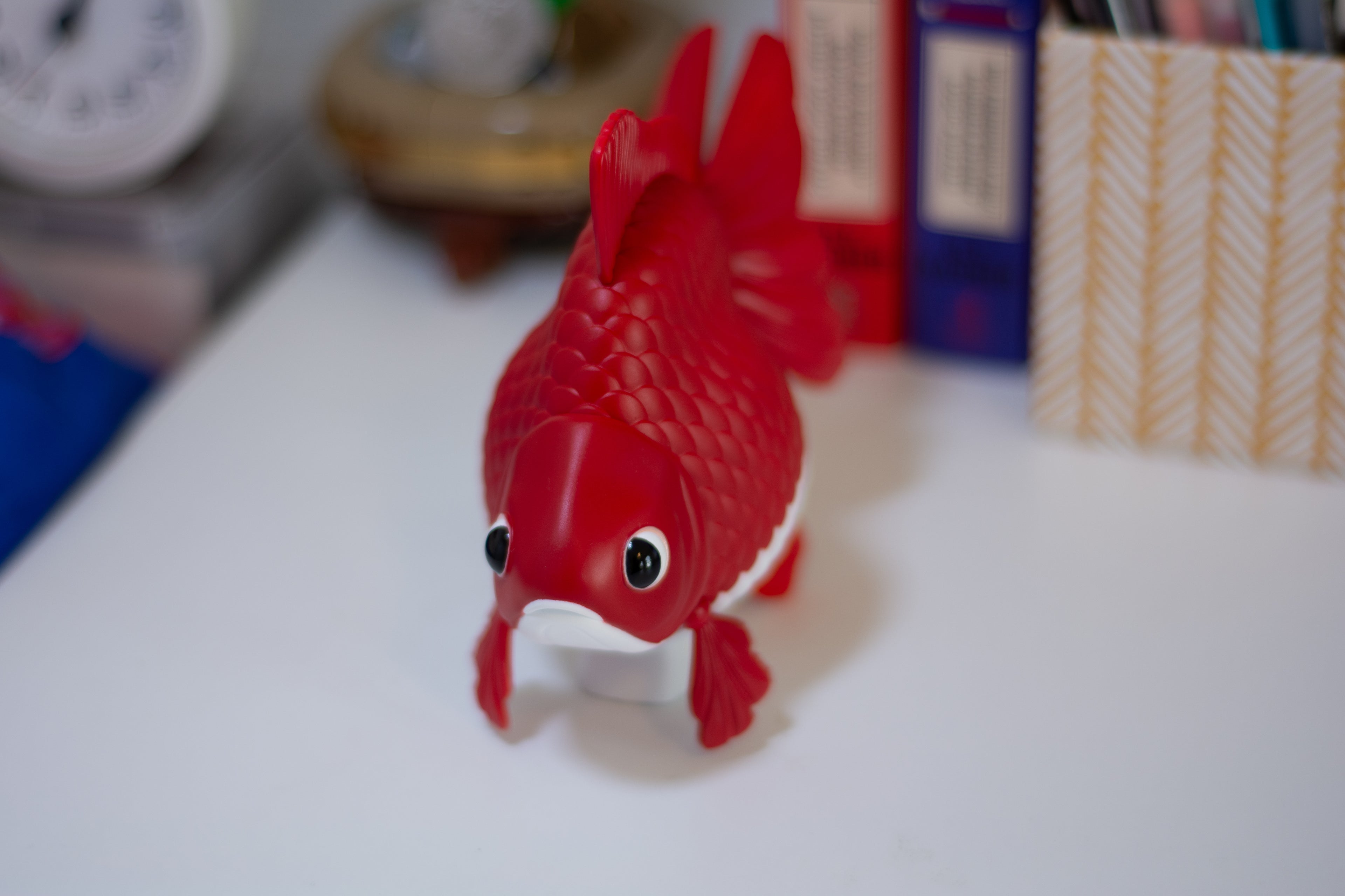 Red fish-shaped toy on a white surface with blurred background